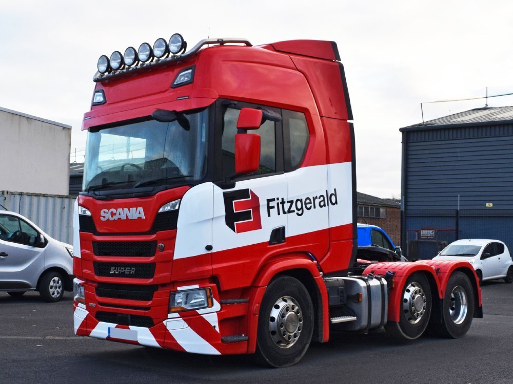 Red and white vehicle wrap with branded vinyl graphics on a Scania truck.