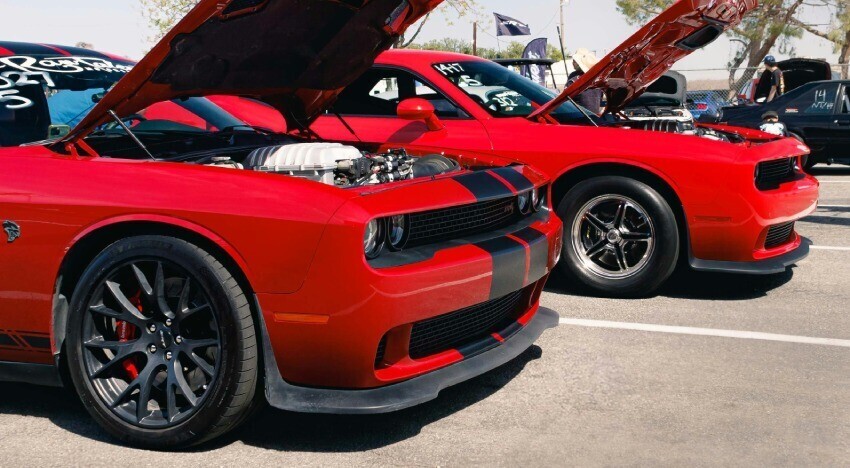 Black striped motorsport graphics on red Dodge Challenger SRT Hellcats at a car show