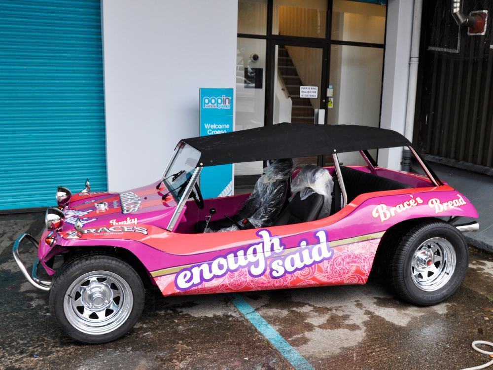 Branded pink marketing vehicle wrap on Volkswagen Meyers Manx.