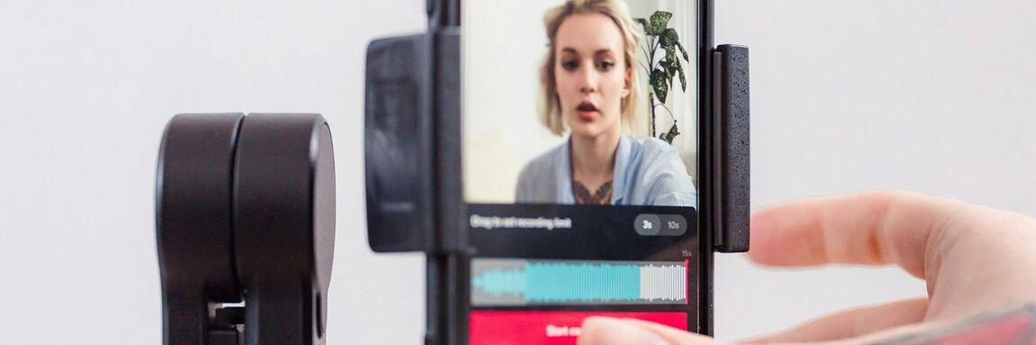 Woman recording on her phone that is attached to a small tripod