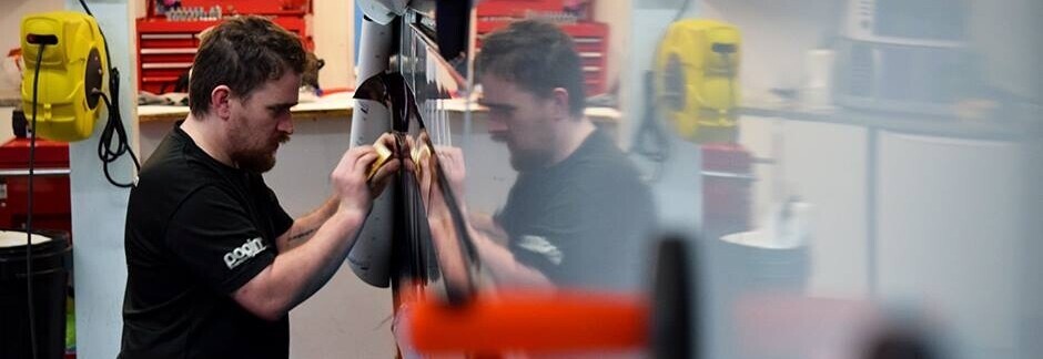 Vehicle vinyl graphics being professionally installed by technician at Popin in Cardiff, South Wales.