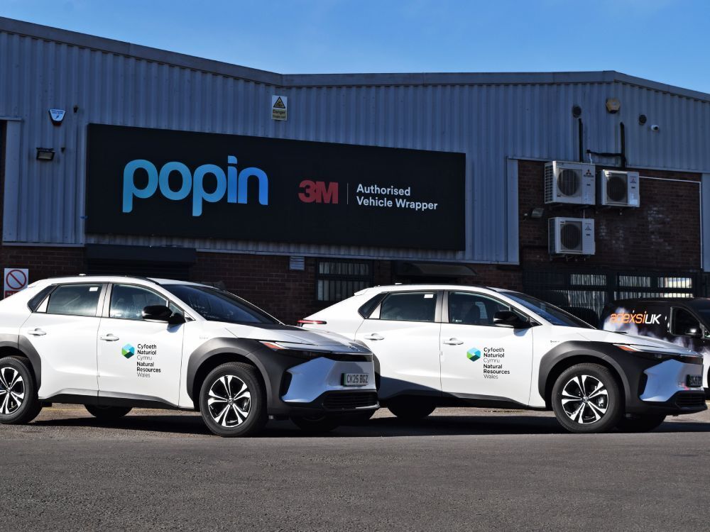 Fleet of Toyota bZ4X electric company vehicles with branded Natural Resources Wales vinyl graphics outside Popin in Cardiff.