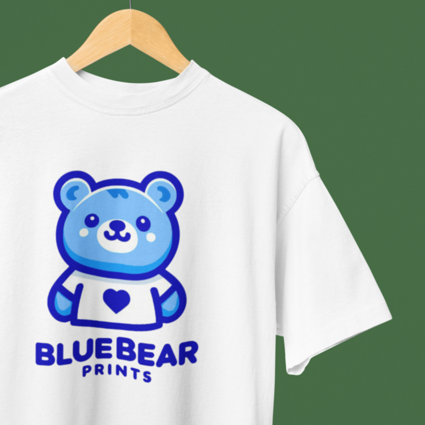 White t-shirt with Blue Bear Prints logo featuring blue bear graphic and text, custom-printed and hung on hanger against green backdrop.