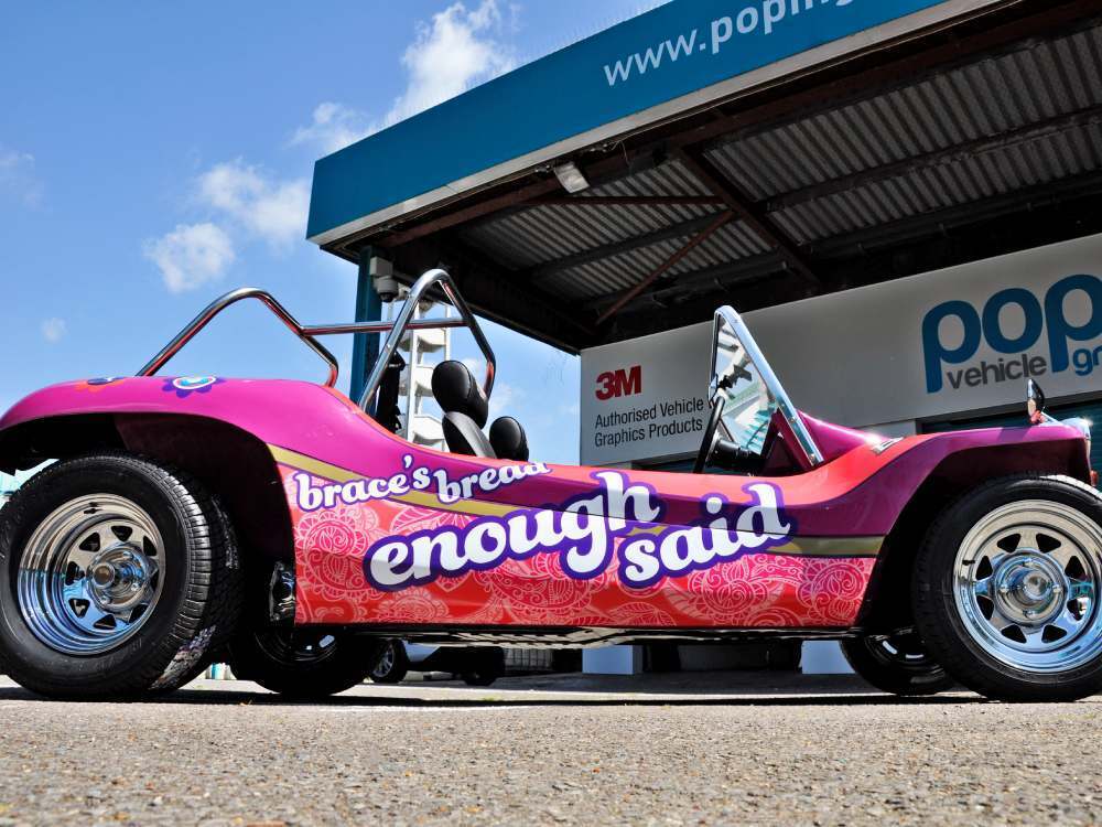 Pink Braces Bread vehicle livery on side of Volkswagen Meyers Manx company car.