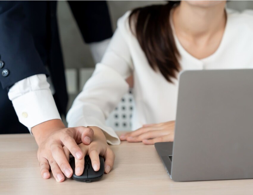 New sexual harassment laws 2026 - a male colleague with his hand over a female colleague's hand on her computer mouse