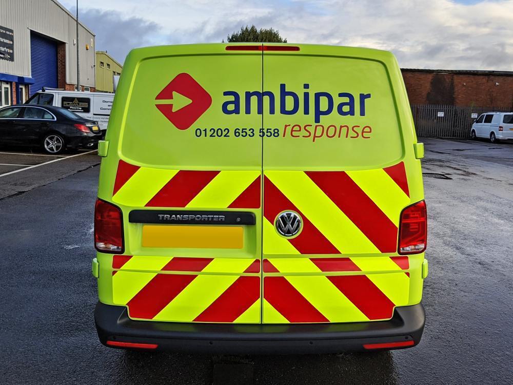 Chevron vinyl graphics on back of yellow Ambipar Response Volkswagen Transporter van.