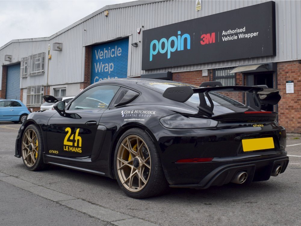 Black motorsport livery with yellow race graphics on a Porsche GT4 RS
