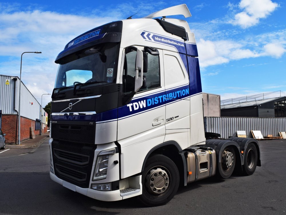 Volvo truck cab with new white vehicle livery and company branded blue vinyl graphics.