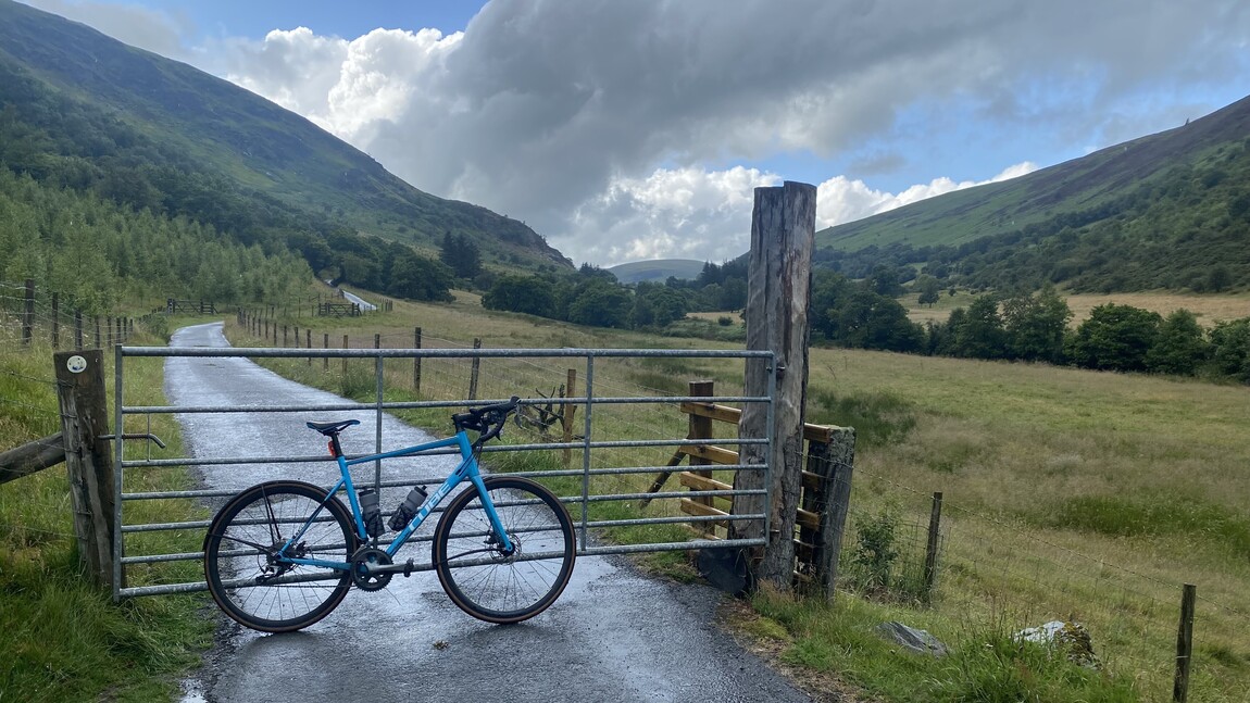 Bicycle leaning against a gate with a stunning scenic backdrop in the Brecon Beacons countryside