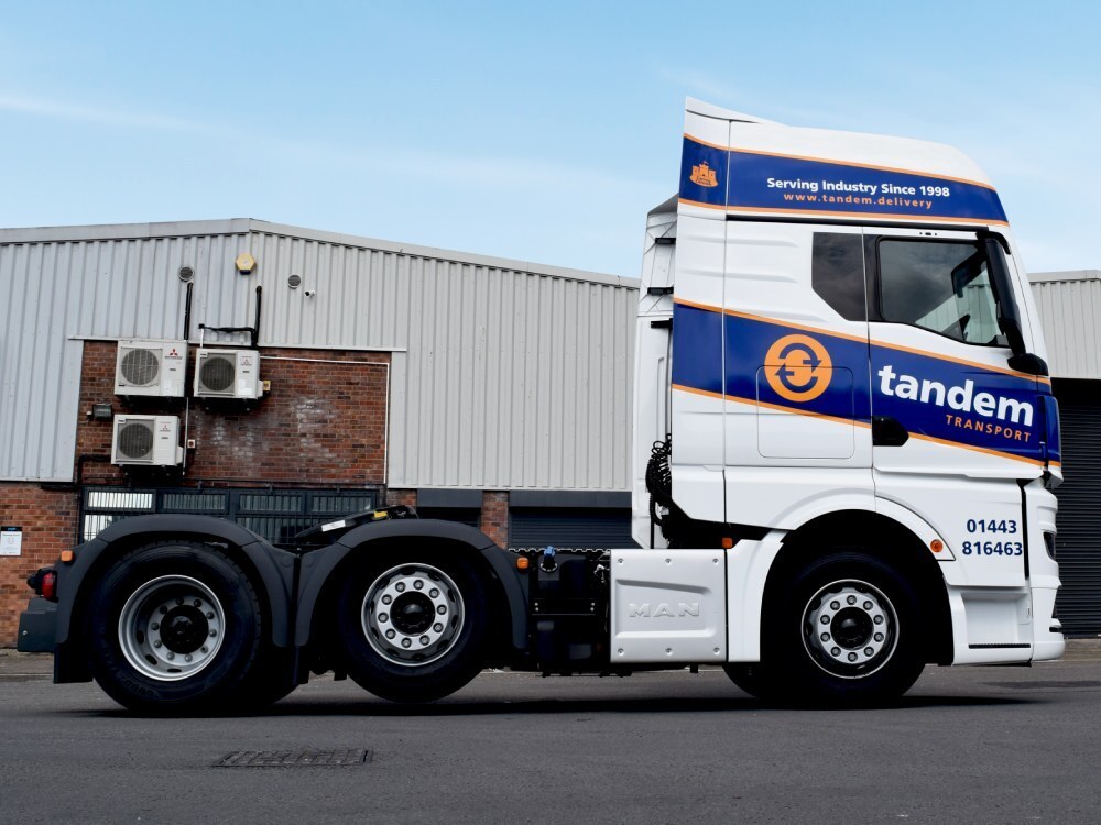 Branded vehicle wrap and graphics on a MAN truck driving on the road.