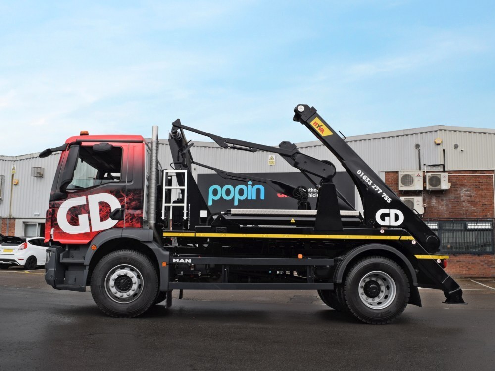 Side profile of a MAN truck with branded vehicle livery and vinyl graphics outside Popin in Cardiff.