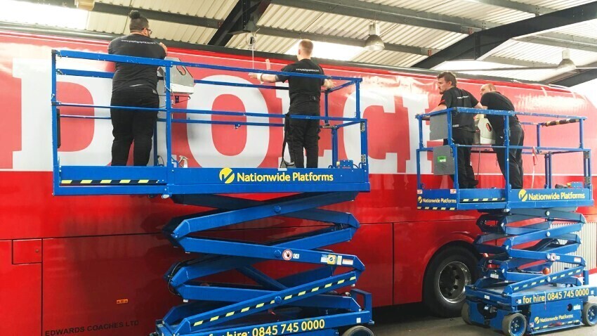 Red FA Wales football team coach vehicle wrap and graphics being installed on Caetano Levante.