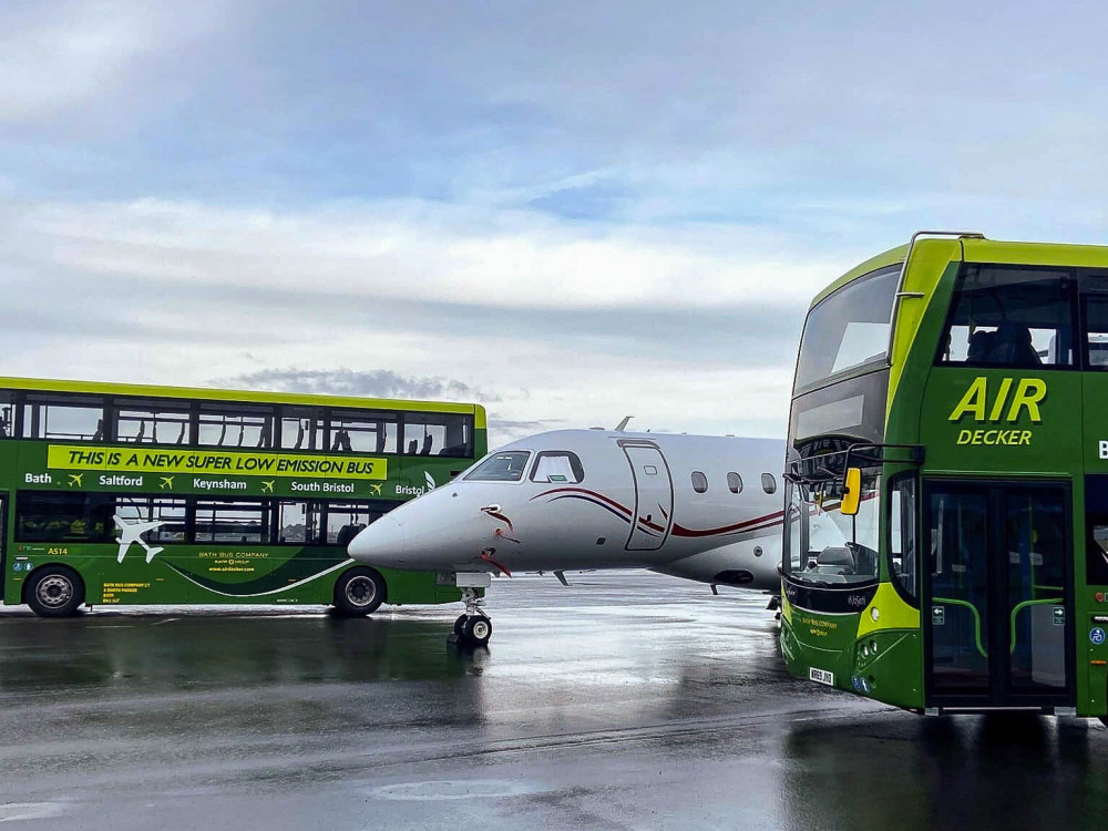 Fleet of Volvo EvoSeti Air Decker buses with matching green livery and commercial graphics at airport with plane.