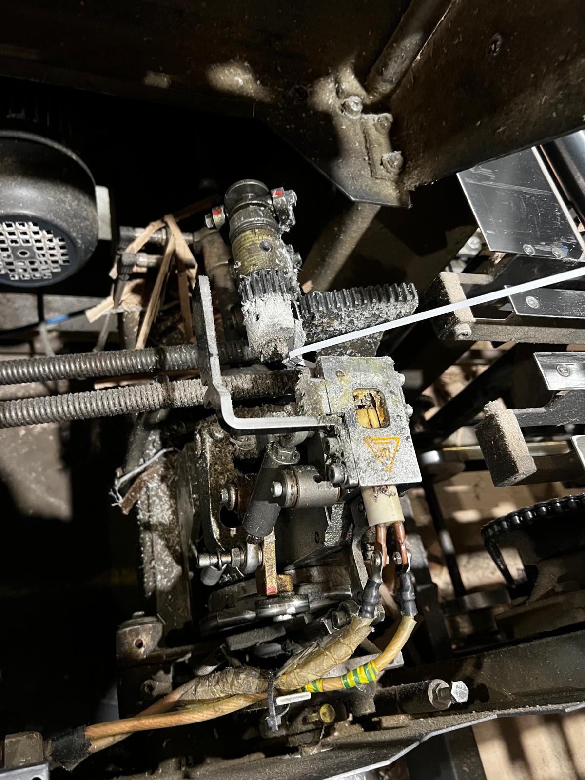 Debris build-up around a strapping machine causing strap path obstruction and jamming