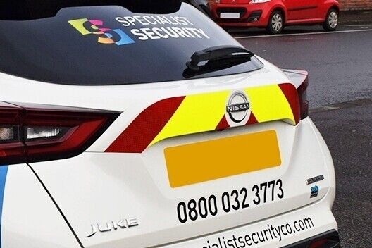 Small safety reflective chevron graphics fitted to the rear of a white Nissan Juke security work vehicle.