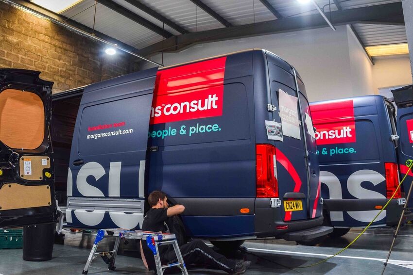 Matching commercial van wraps and vinyl graphics being installed on a fleet of vehicles at Popin in Cardiff.