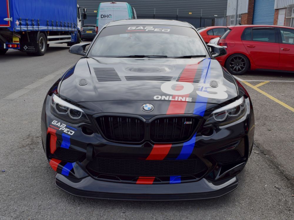 Motorsport livery and decals on front end of a black BMW M2 race car