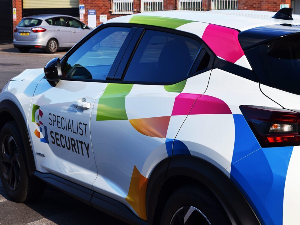 Nissan Juke Hybrid with company branded vehicle graphics for Specialist Security.