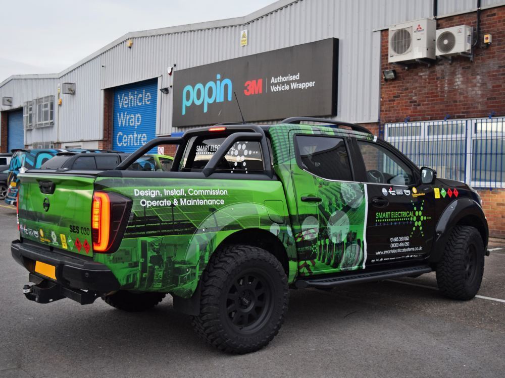 Green reflective vehicle wrap and graphics on company Nissan Navara outside Popin in Cardiff.