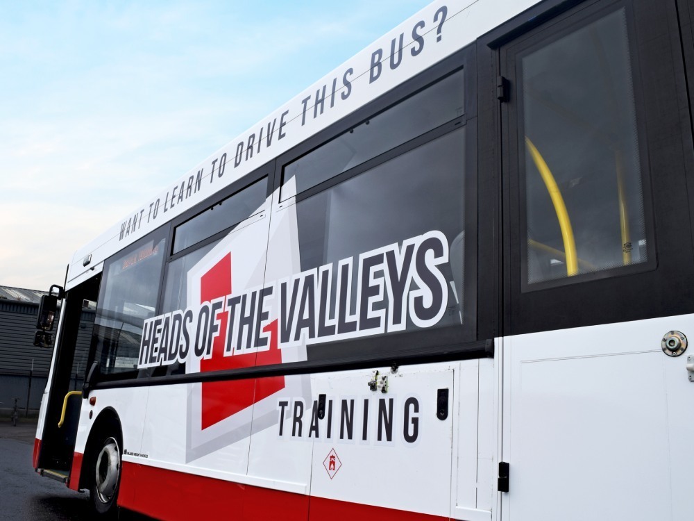 Company branded vinyl graphics on red and white Alexander Dennis Enviro 300 driver training bus.