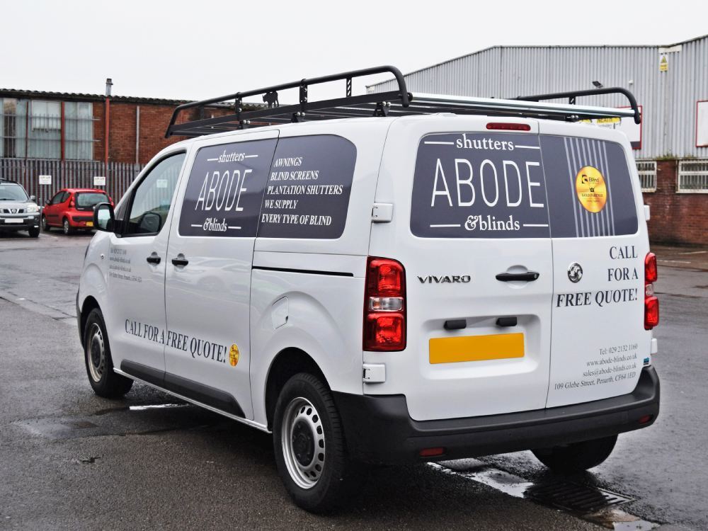 Rear white Vauxhall Vivaro van with company advertising vinyl graphics.