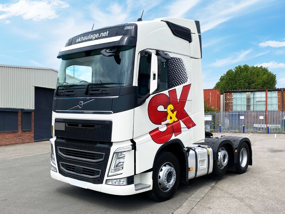 White vehicle wrap and branded vinyl graphics installed on a Volvo truck cab.