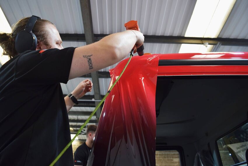 Vehicle wrap technician at Popin in Cardiff professionally applying vinyl livery to truck.