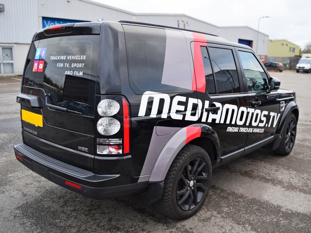 Branded vehicle graphics on a black company Land Rover Discovery.