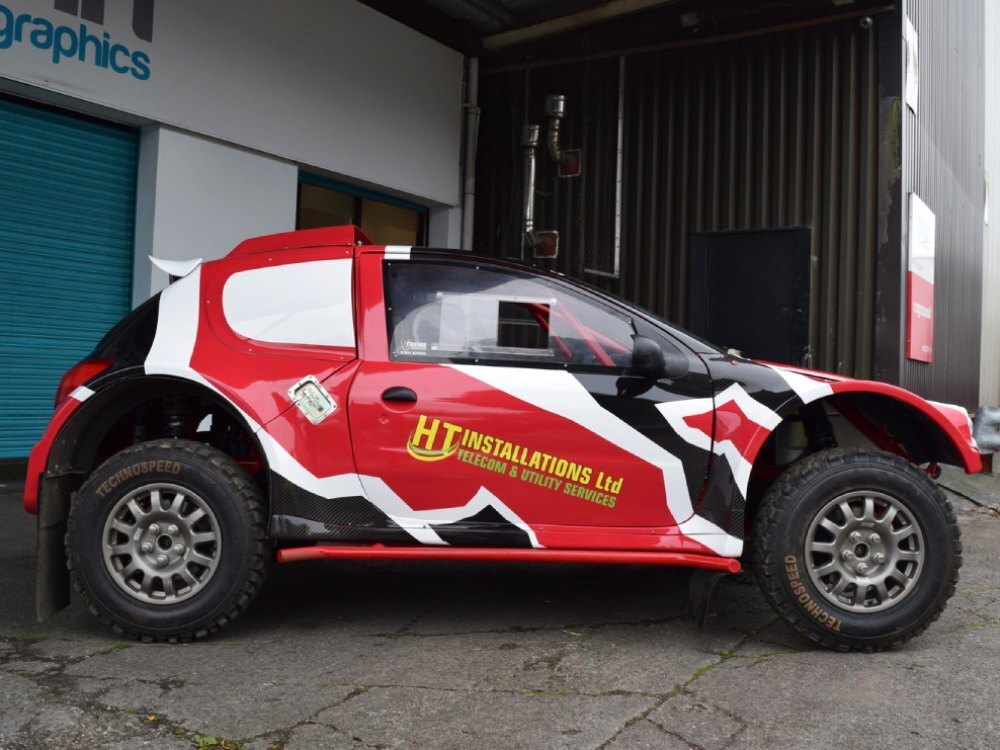Red, white and black motorsport livery and race graphics on a Peugeot 206 rally car