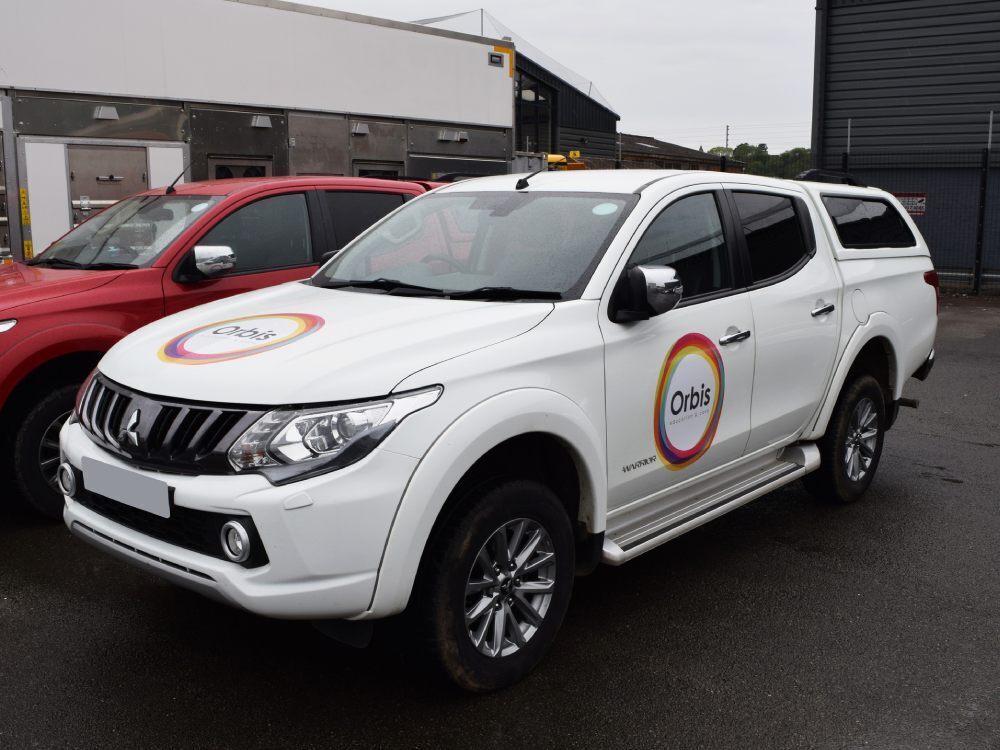Branded vinyl graphics on white company Mitsubishi L200.