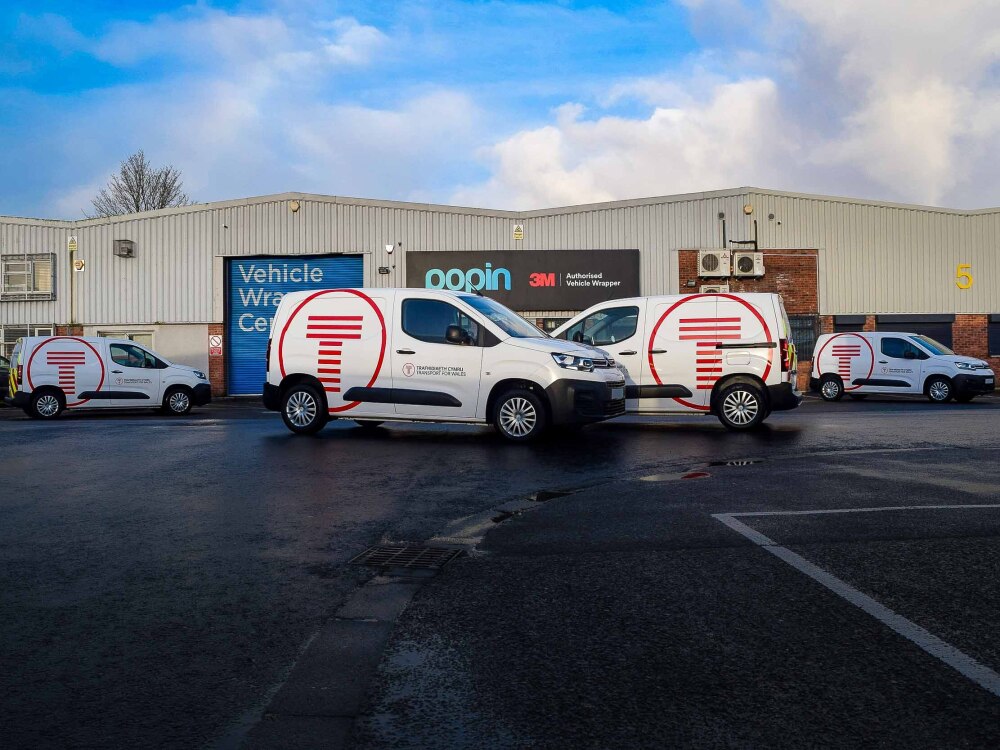 Fleet of Citroen Berlingo vans with matching red Transport for Wales branded vinyl graphics outside Popin in Cardiff.