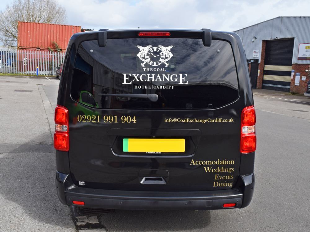 Company branded vinyl van graphics on rear end of black Vauxhall Vivaro.