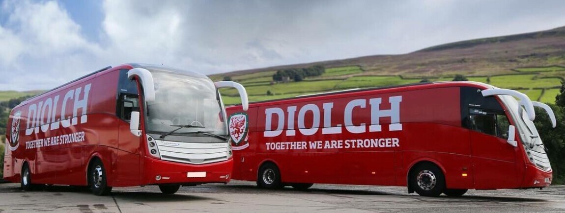 Fleet of coaches for Welsh national football team with matching red vehicle wraps.