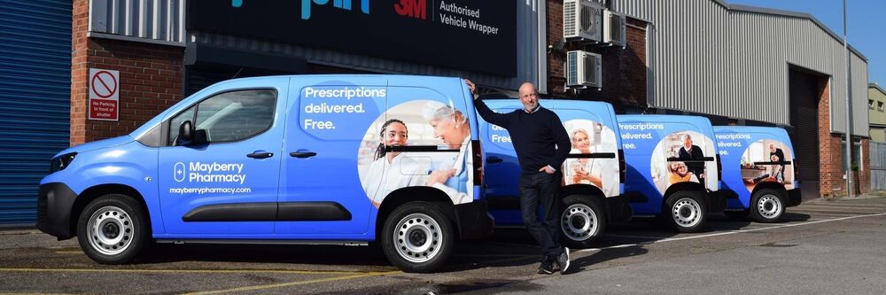 Fleet of vans with consistent livery branding for Mayberry Pharmacy parked outside Popin vehicle wrap centre in Cardiff.