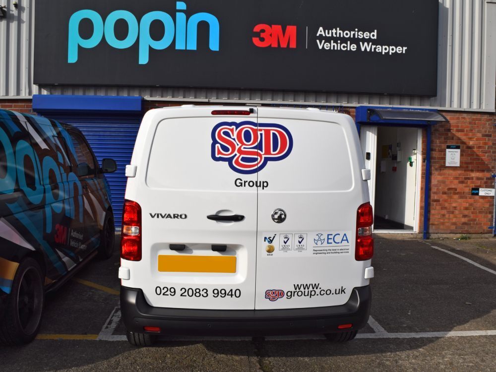 Company branded vinyl graphics on rear of white Vauxhall Vivaro van outside Popin in Cardiff.