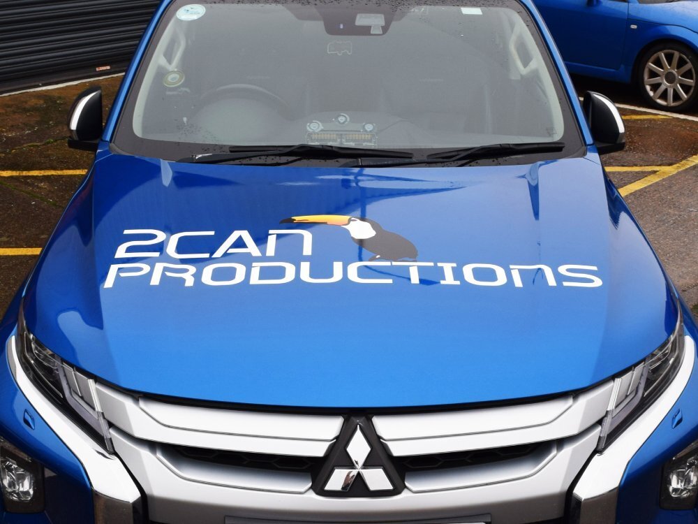 Branded vinyl graphics on bonnet of blue company Mitsubishi L200.