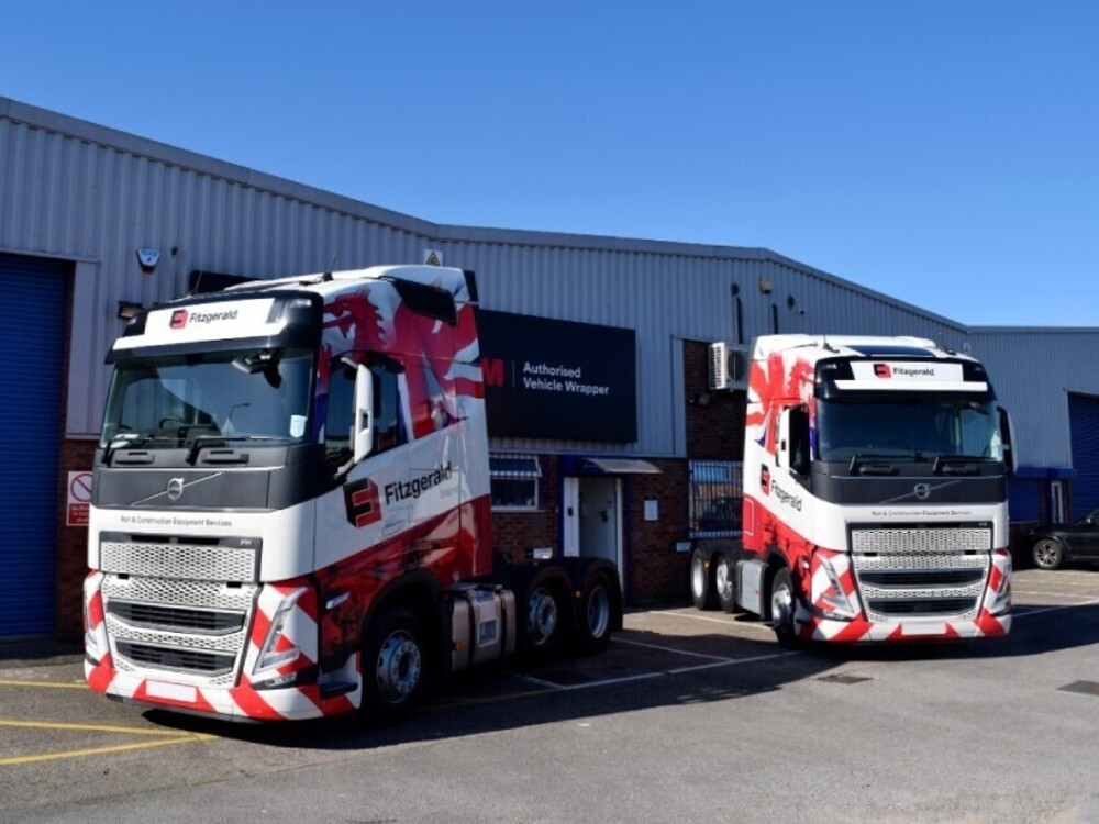Fleet of two Volvo trucks outside Popin with matching red and white vinyl liveries.