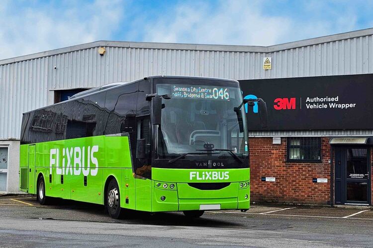Van Hool Flixbus coach with green full wrap and white branded vehicle graphics outside Popin in Cardiff.