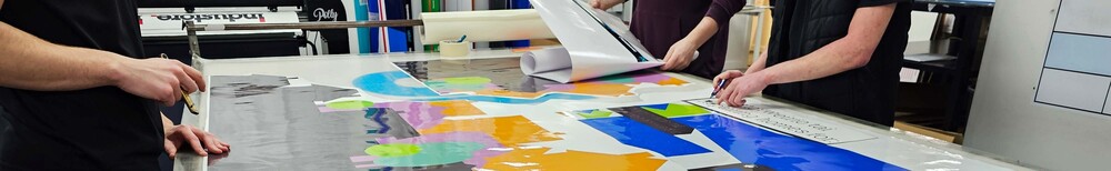 Vehicle wrap technicians cutting printed vinyl graphics to size at Popin workshop.