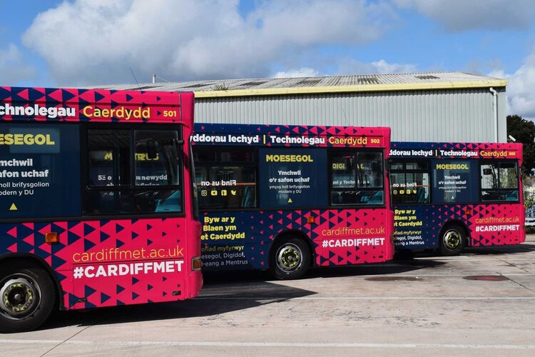 Public bus fleet with matching branded vehicle wraps and promotional vinyl graphics.