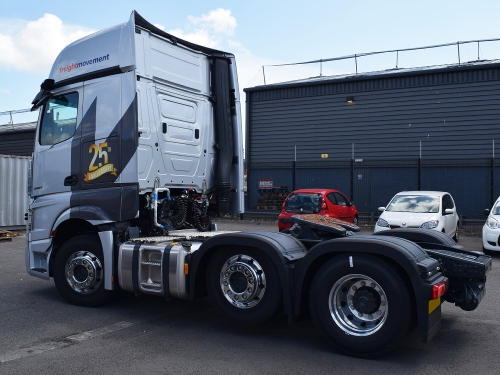 Silver livery and branded vehicle graphics on a Mercedes lorry.