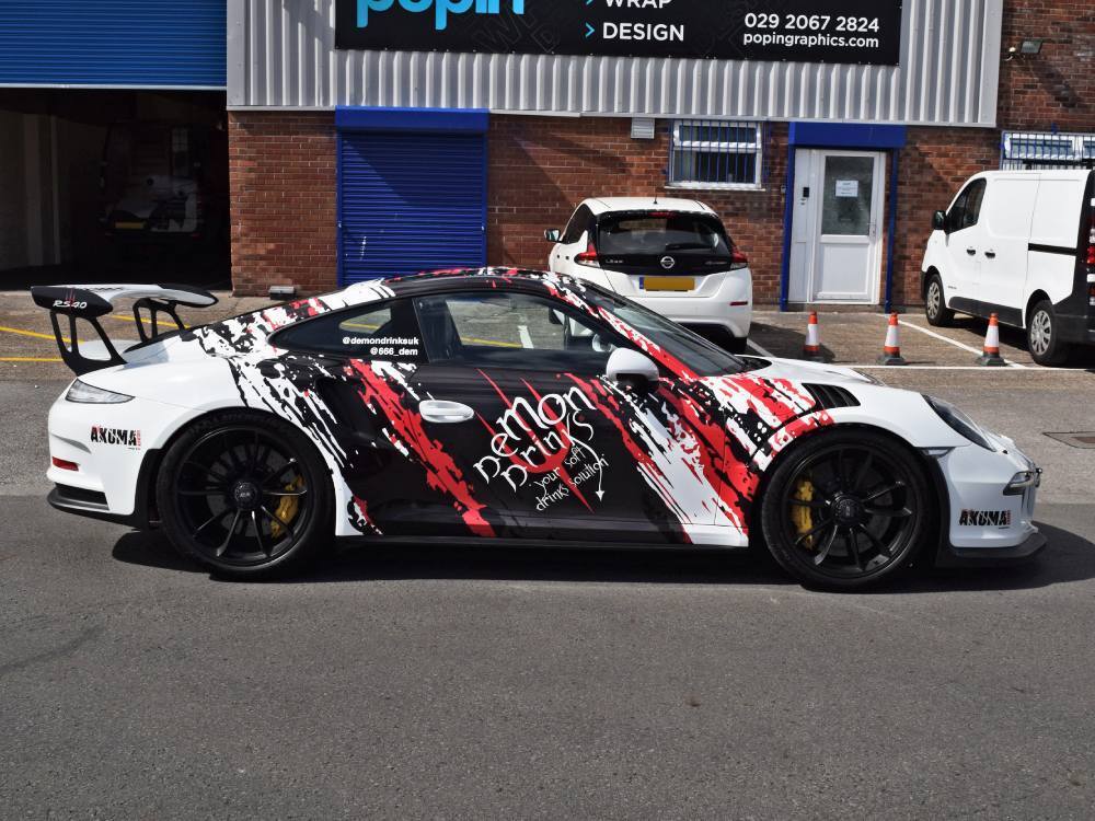 Creative vehicle wrap on white company Porsche GT3 RS outside Popin in Cardiff.