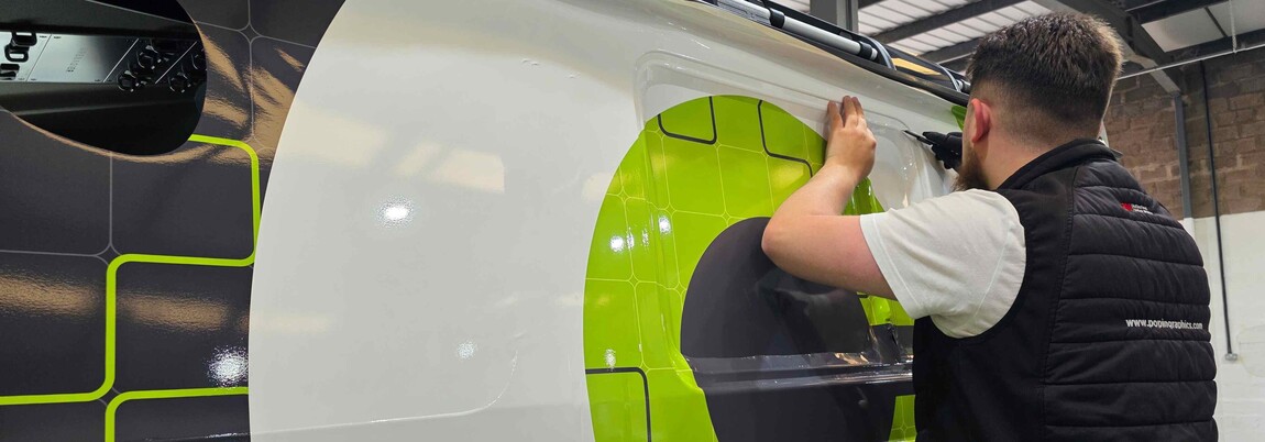 Vehicle wrap technician installing branded premium vinyl material onto a company van.