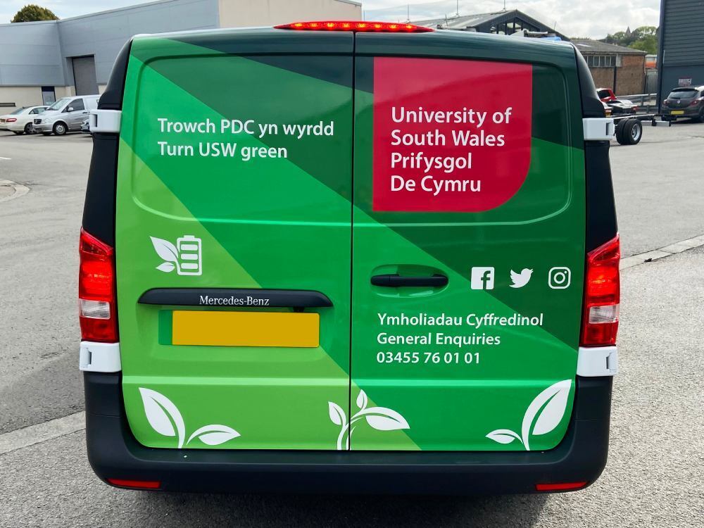 Green University of South Wales branded vehicle livery on back of Mercedes-Benz eVito electric van.