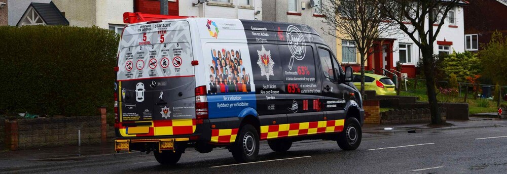 Reflective chevron vehicle graphics on a UK South Wales Fire and Rescue Service van.