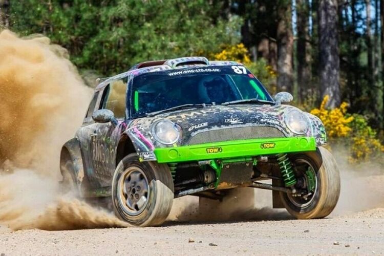Mini Cooper V6 rally car with colourful bespoke motorsport livery and graphics during off-road race.
