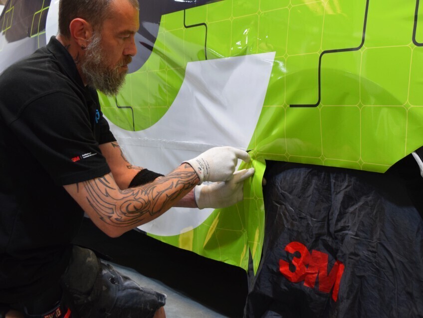 Branded vehicle wrap being installed onto a company EV van.