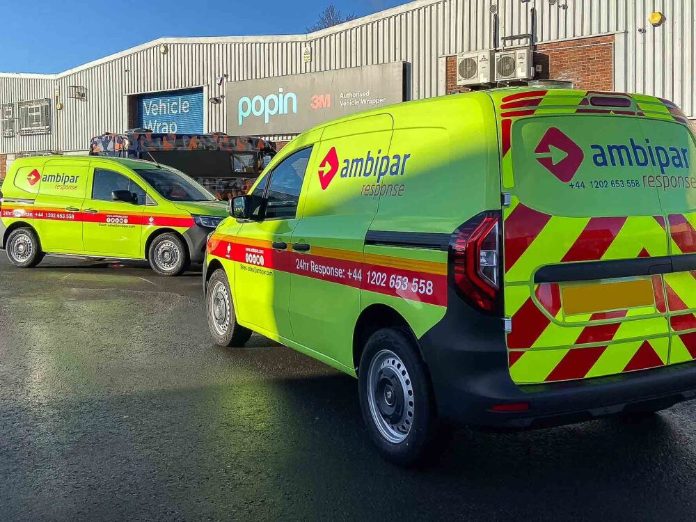 Fleet of Renault Kangoo vans for Ambipar Response with matching fluorescent yellow vehicle wraps and chevron graphics outside Popin in Cardiff.