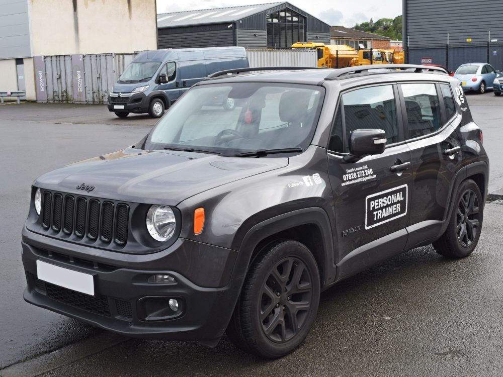 Grey company Jeep with white branded vehicle graphics.