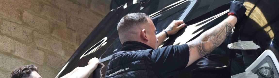 Vehicle wrap technician at Popin applying premium vinyl wrap to the front of a well prepared truck.